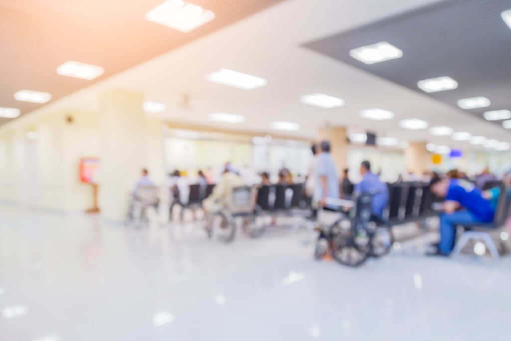 Blurred hospital waiting area with patients seated, illustrating emergency department flow and patient wait times